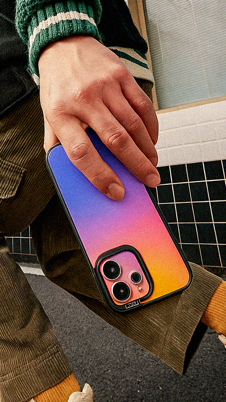 Person on a skateboard holding a colorful phone case, with a building and clear sky in the background.